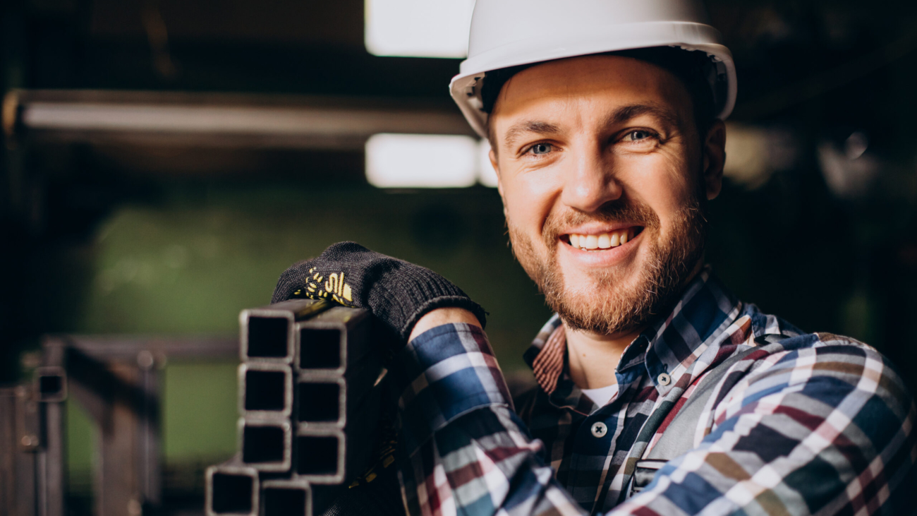 Workman wearing hard hat working with metal constructions at factory