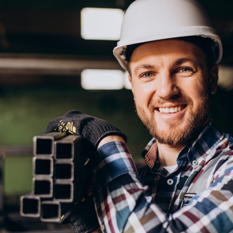 Workman wearing hard hat working with metal constructions at factory
